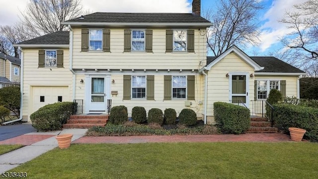 colonial-style house featuring a garage and a front yard