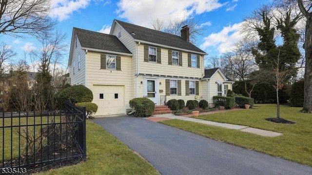 colonial inspired home with a garage and a front yard