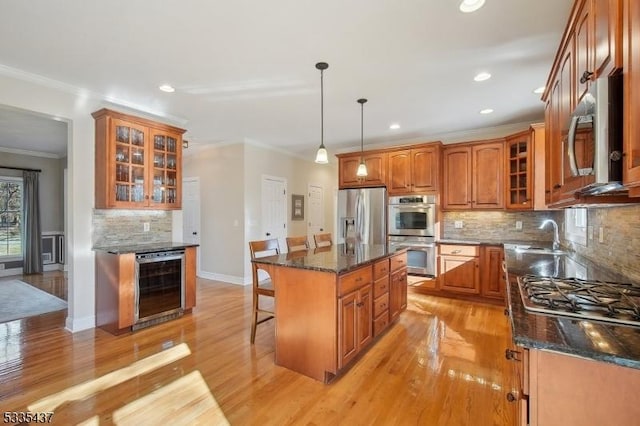 kitchen featuring wine cooler, a center island, appliances with stainless steel finishes, pendant lighting, and dark stone counters