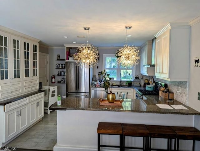 kitchen with sink, appliances with stainless steel finishes, a notable chandelier, a kitchen bar, and decorative light fixtures