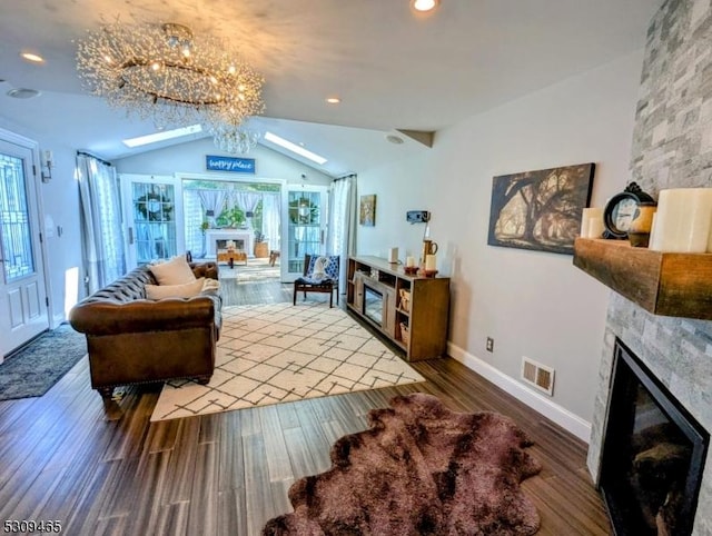 living room featuring hardwood / wood-style flooring, lofted ceiling, a fireplace, and a notable chandelier