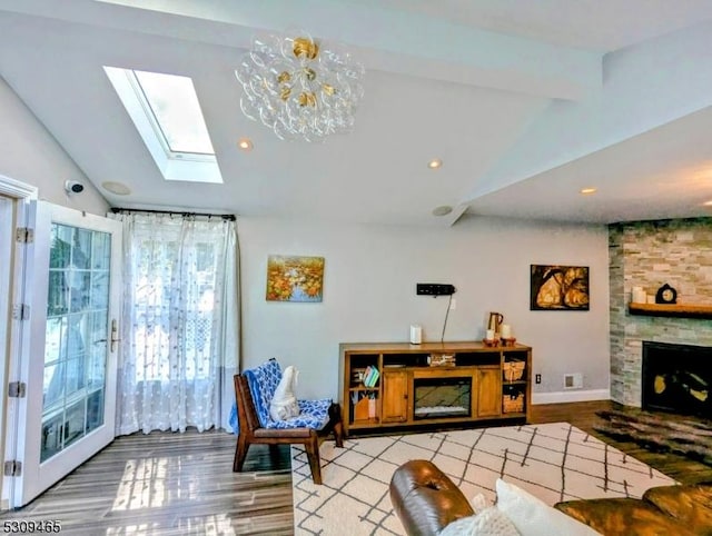 living room with light hardwood / wood-style flooring, lofted ceiling with skylight, and a large fireplace