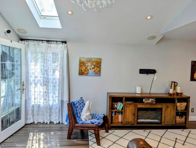 sitting room with light hardwood / wood-style flooring, lofted ceiling with skylight, and a healthy amount of sunlight