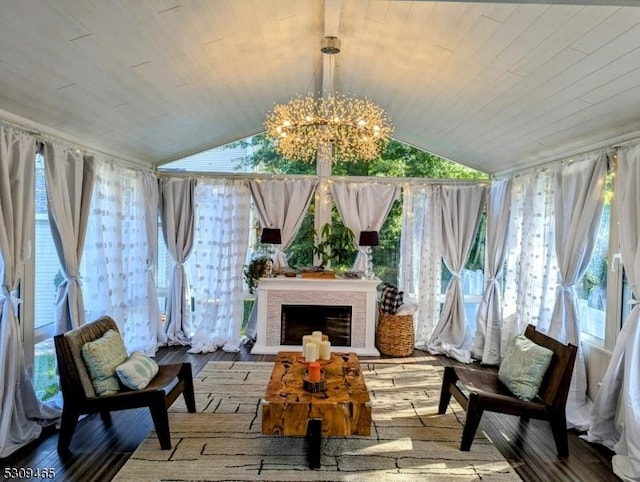 sitting room featuring an outdoor fireplace, a chandelier, vaulted ceiling, and light hardwood / wood-style flooring