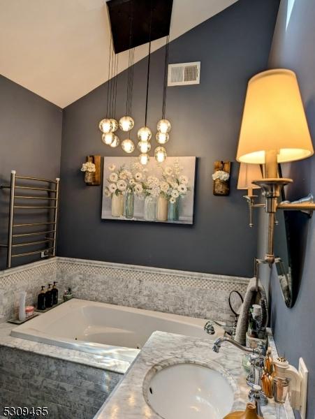 bathroom with vanity, radiator, and vaulted ceiling