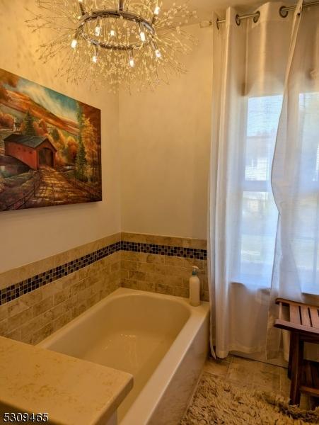 bathroom featuring a chandelier and a washtub