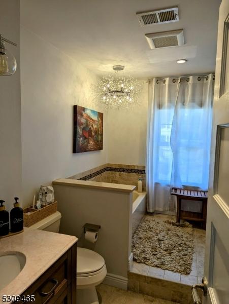 bathroom with an inviting chandelier, tile patterned floors, vanity, and toilet