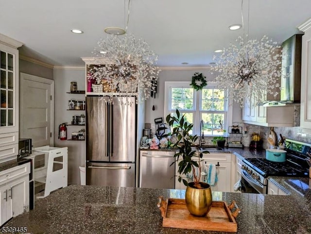 kitchen with appliances with stainless steel finishes, dark stone counters, hanging light fixtures, and white cabinets