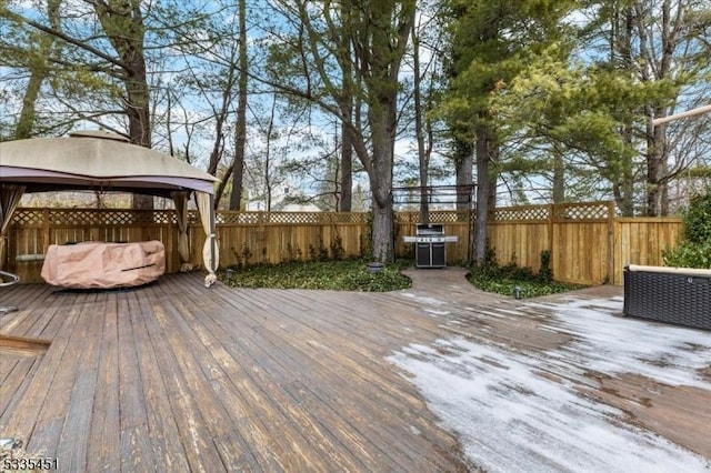 wooden deck with a gazebo, a fenced backyard, and a grill