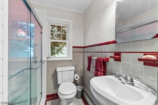 bathroom with toilet, a sink, crown molding, a shower stall, and tile walls