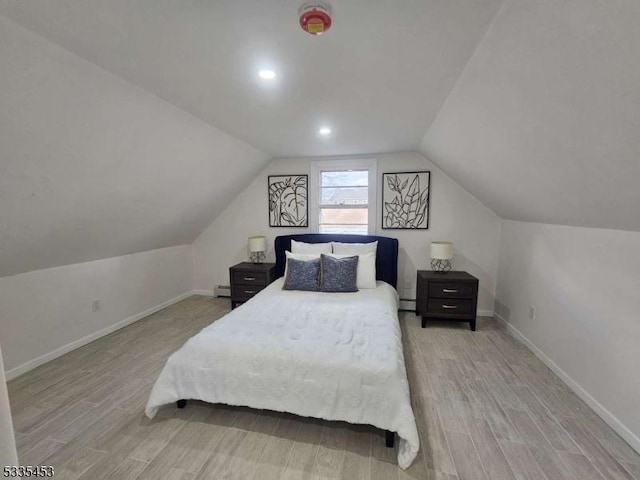 bedroom with lofted ceiling, a baseboard radiator, and light wood-type flooring