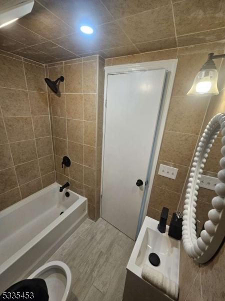 bathroom with hardwood / wood-style floors and tiled shower / bath