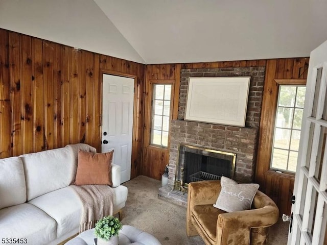 living room with carpet floors, a brick fireplace, wooden walls, and lofted ceiling