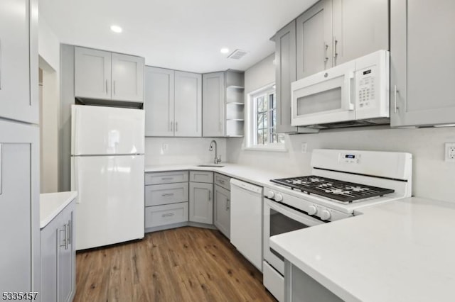 kitchen with sink, white appliances, gray cabinets, and dark hardwood / wood-style floors