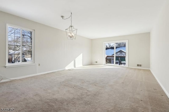 carpeted spare room with an inviting chandelier