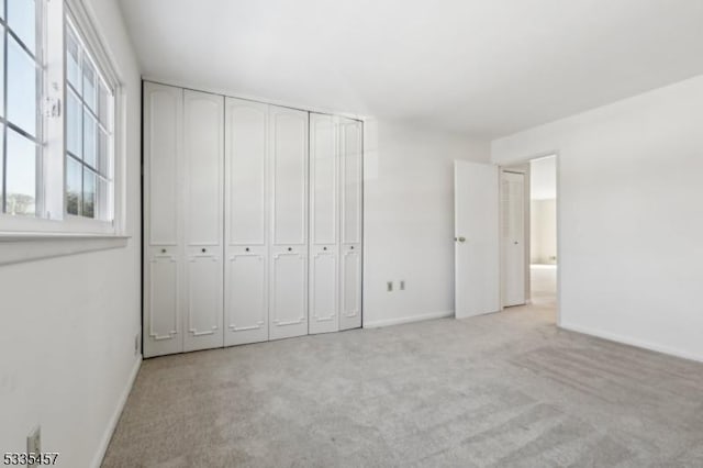 unfurnished bedroom with light colored carpet and a closet