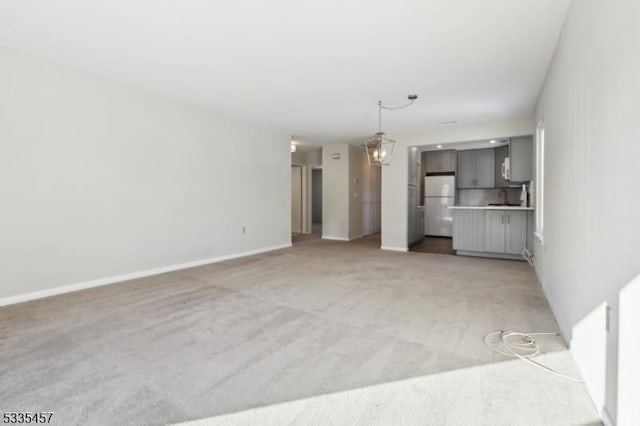 unfurnished living room featuring light colored carpet and a chandelier