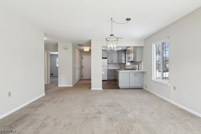 unfurnished living room featuring carpet floors, sink, and a chandelier