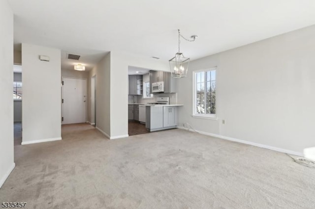 unfurnished living room with an inviting chandelier and carpet floors