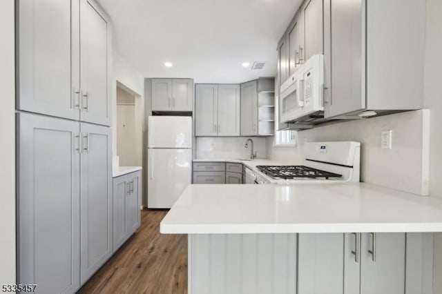 kitchen with white appliances, gray cabinets, kitchen peninsula, and sink