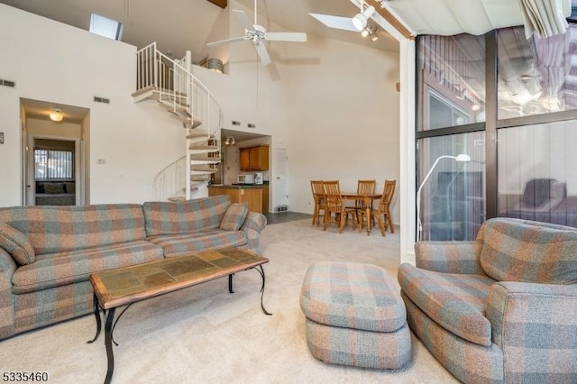 living room with lofted ceiling with skylight, light colored carpet, and ceiling fan