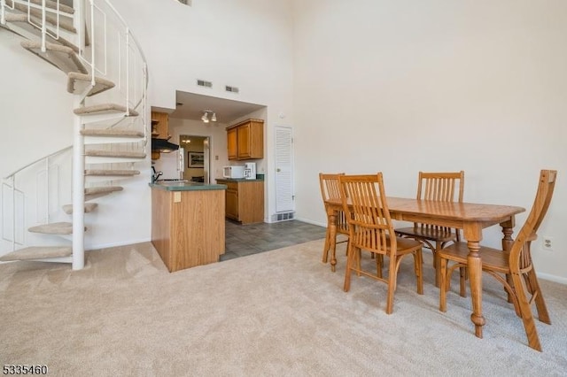 carpeted dining space featuring a towering ceiling