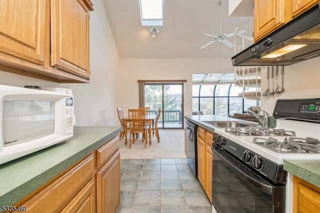 kitchen with vaulted ceiling with skylight, range with gas cooktop, sink, dishwashing machine, and ceiling fan