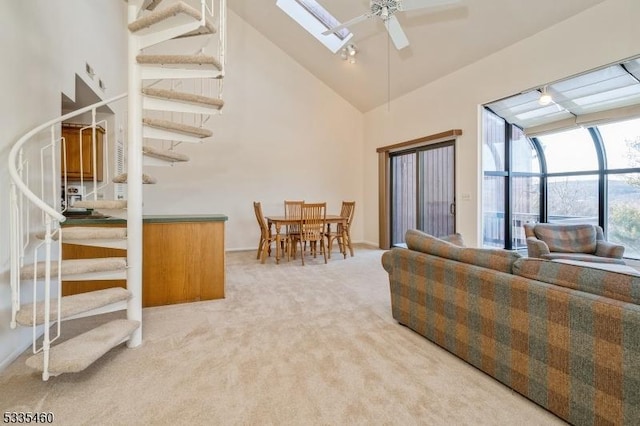 living room featuring ceiling fan, high vaulted ceiling, and light carpet