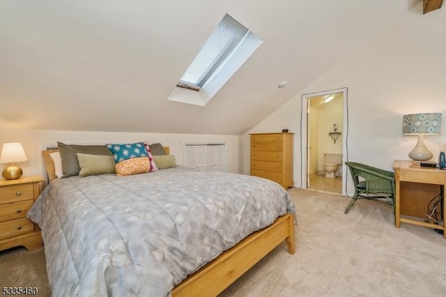 bedroom with ensuite bathroom, carpet flooring, and vaulted ceiling with skylight