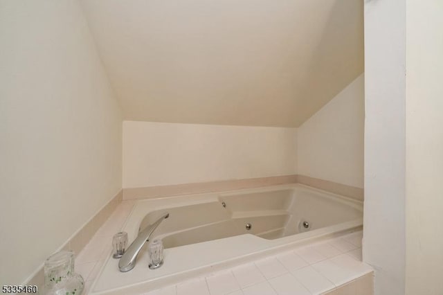 bathroom with lofted ceiling and tiled bath