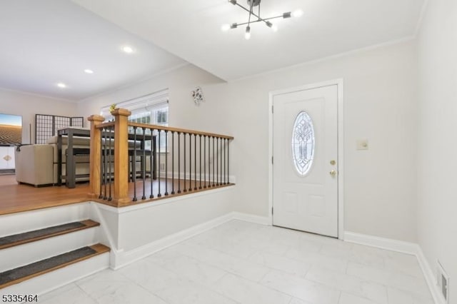 foyer with crown molding and a chandelier