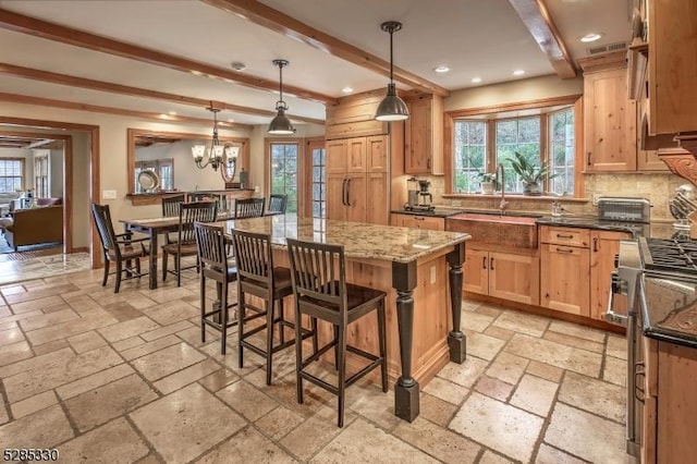 kitchen featuring decorative light fixtures, a center island, high end stainless steel range oven, dark stone counters, and decorative backsplash