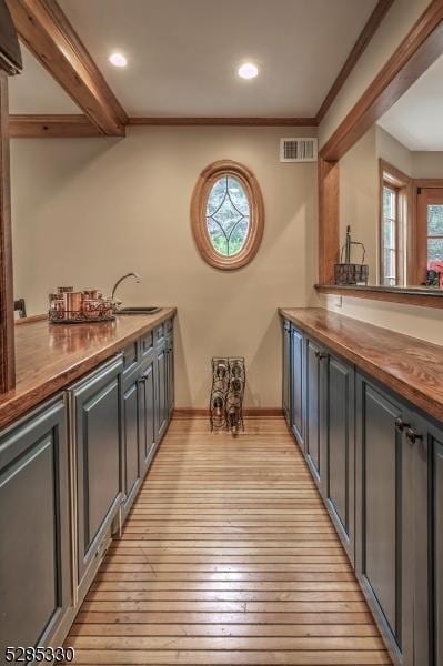 bar featuring ornamental molding, sink, and light wood-type flooring