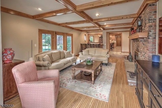 living room featuring coffered ceiling, a fireplace, light hardwood / wood-style floors, and beamed ceiling