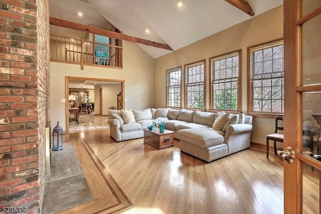 living room with light hardwood / wood-style flooring, a wealth of natural light, and beamed ceiling