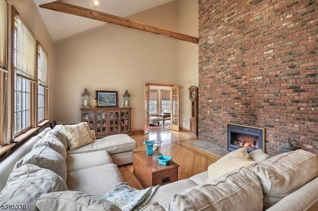 living room with a brick fireplace, a wealth of natural light, and high vaulted ceiling