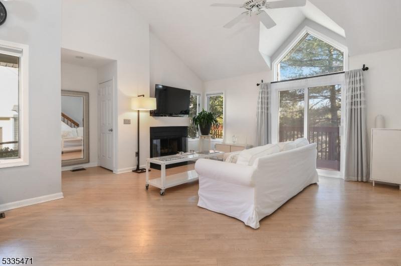 living room with ceiling fan, high vaulted ceiling, and light hardwood / wood-style flooring