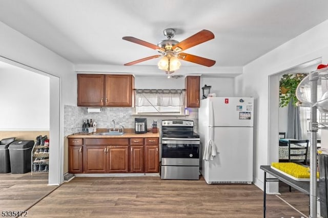 kitchen with stainless steel electric range oven, white fridge, sink, and dark wood-type flooring