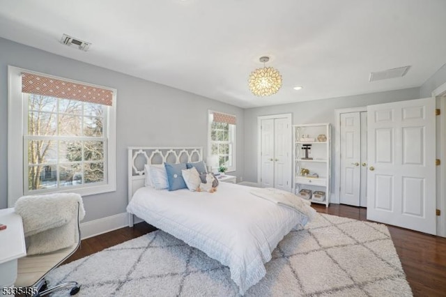 bedroom with dark wood-type flooring and two closets