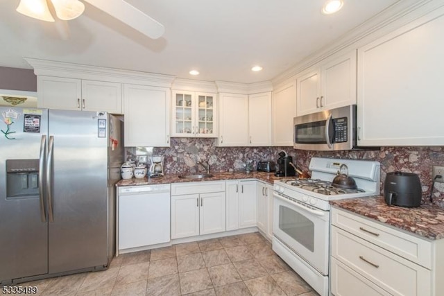 kitchen with appliances with stainless steel finishes, white cabinetry, sink, dark stone countertops, and backsplash