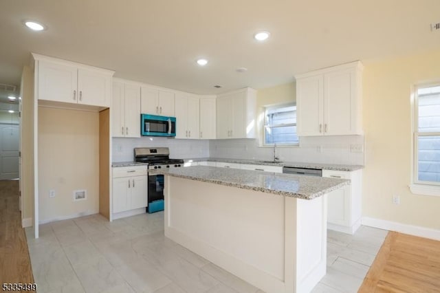 kitchen with stainless steel appliances, white cabinetry, and a center island