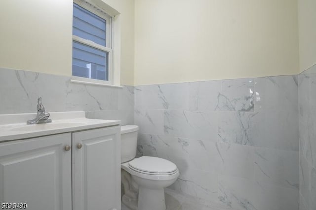 bathroom featuring vanity, tile walls, and toilet