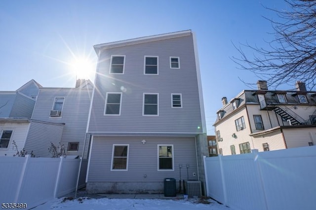 snow covered rear of property featuring cooling unit