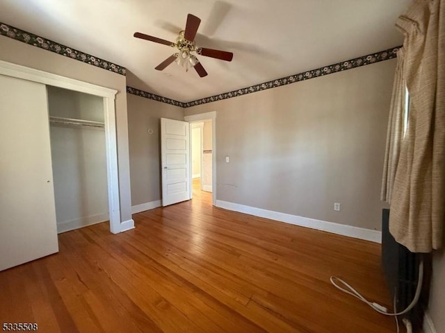 unfurnished bedroom featuring ceiling fan, hardwood / wood-style floors, and a closet