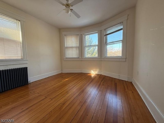 unfurnished room featuring radiator, wood-type flooring, and ceiling fan