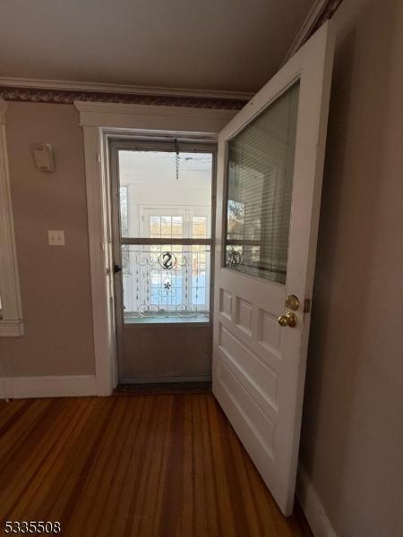 doorway with hardwood / wood-style flooring and crown molding