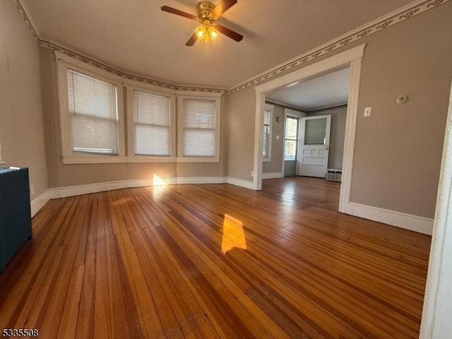 interior space featuring wood-type flooring, ornamental molding, and ceiling fan