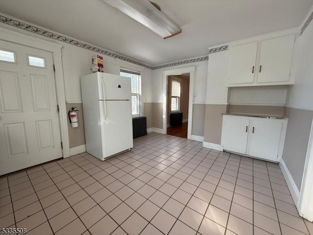 kitchen with light tile patterned floors, white cabinets, and white fridge