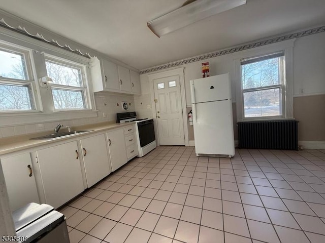 kitchen with sink, white appliances, backsplash, radiator heating unit, and white cabinets