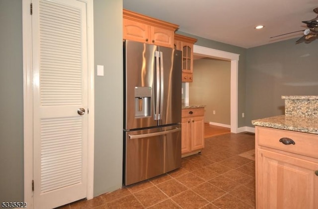 kitchen featuring dark tile patterned flooring, ceiling fan, stainless steel refrigerator with ice dispenser, light stone countertops, and light brown cabinets